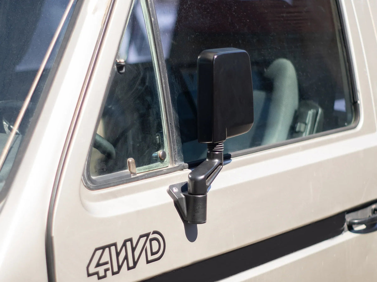 GoWesty Deluxe Manual Mirror Kit for Vanagon, showing two side mirrors with black frames and mounting hardware on a vehicle.