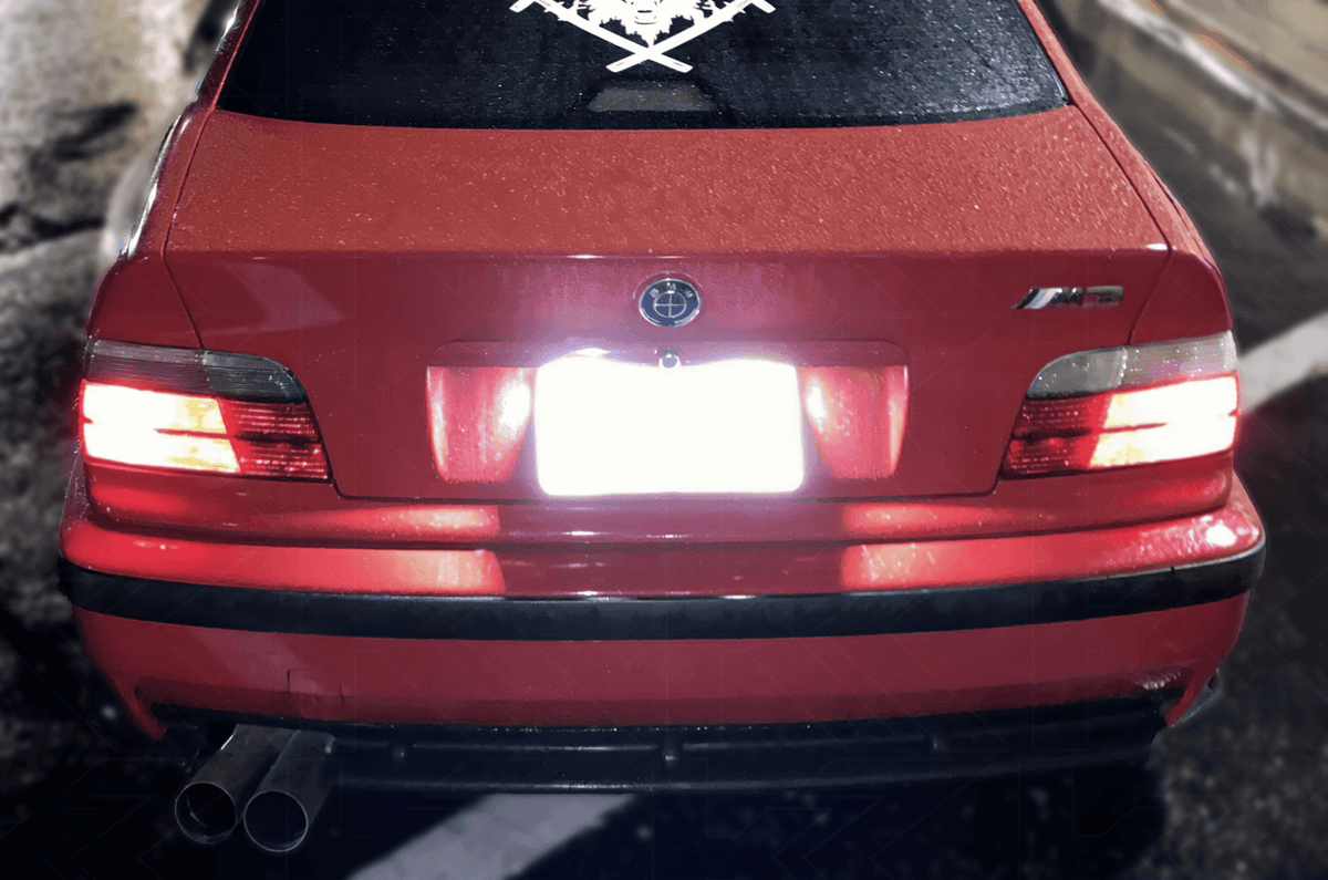K2 Industries LED license plate lights for BMW E36 1992-1999, super bright bulbs installed on a vehicle's license plate area.