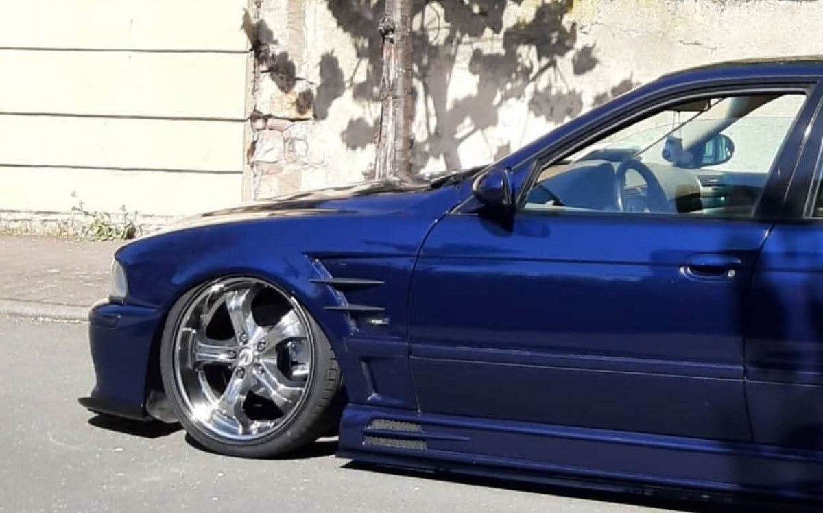 K2 Industries Rieger BMW E39 Vented Side Skirts V1 installed on black BMW E39 sedan, showcasing sleek aerodynamic design