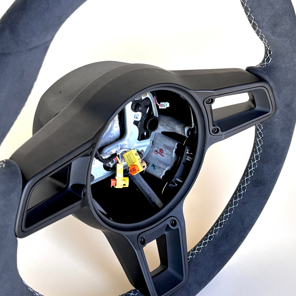 Red manual Porsche 991.2 steering wheel by Boston Motortech, showing textured leather grip and detailed brand logo on center hub.