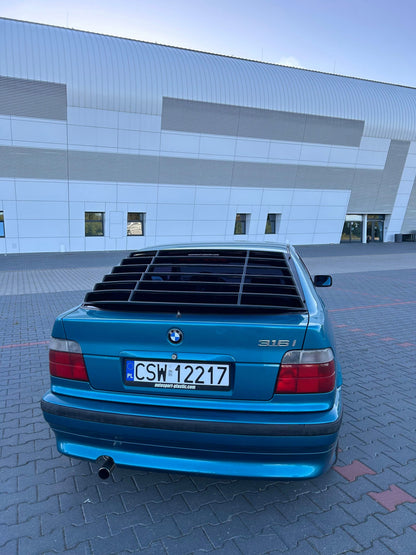 Black BMW E36 Compact Series 3 windshield louvers by K2 Industries, shown installed on the rear window, enhancing sporty style.