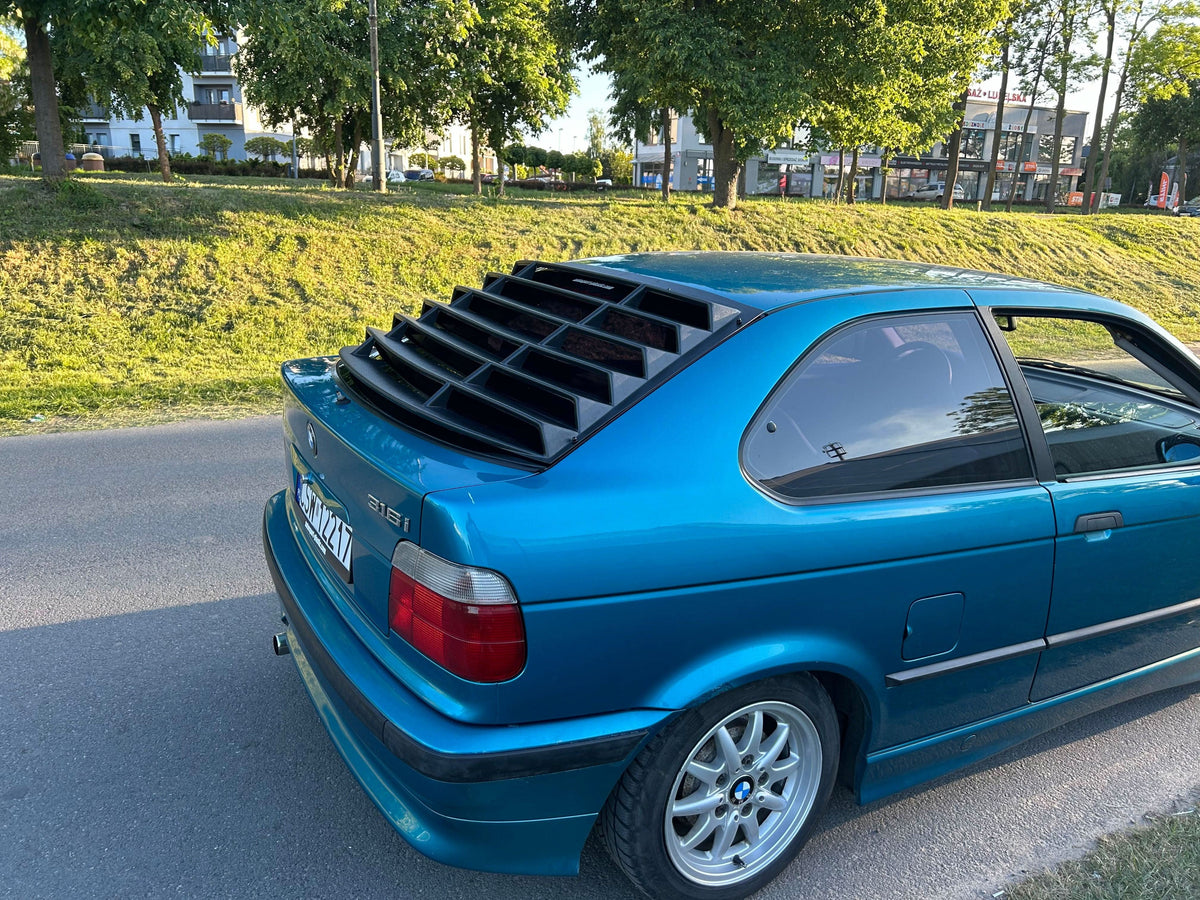 BMW E36 Compact Series 3 black back windshield louvers by K2 Industries, shown on the rear window of the car.