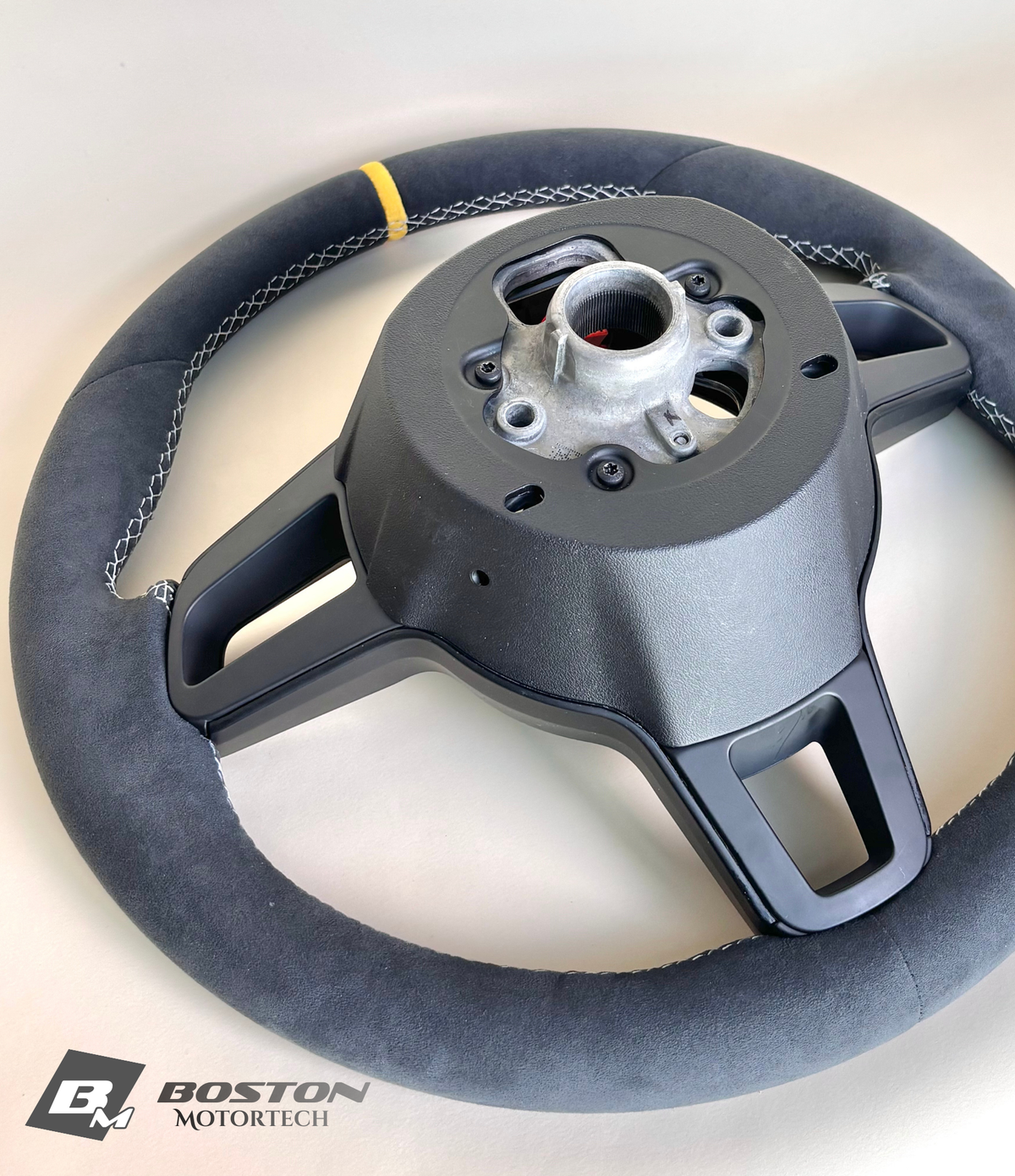 Yellow manual Porsche 991.2 steering wheel by Boston Motortech with black accents and textured grip, shown in close-up.