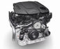 Audi V6 TDI engine with a black plastic engine cover, silver metallic components, and black belts, shown on a light gray background.