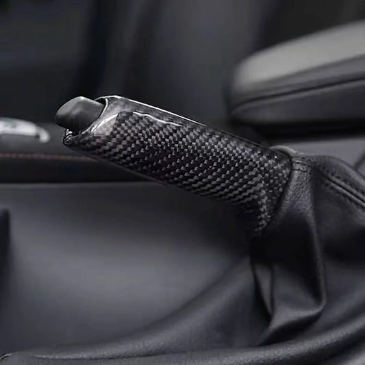BMW carbon fiber handbrake lever cover by K2 Industries, showing sleek black carbon fiber material on a handbrake lever.