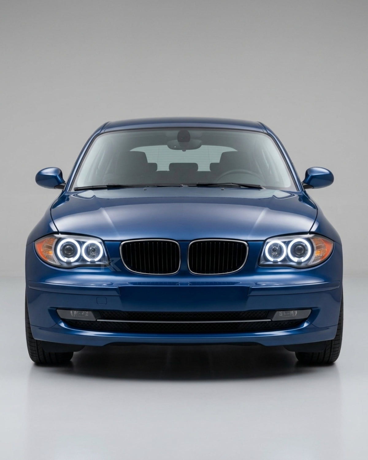 BMW 1 Series E87 headlights with LED angel eyes, K2 Industries brand, showing the front view with illuminated angel eye rings.