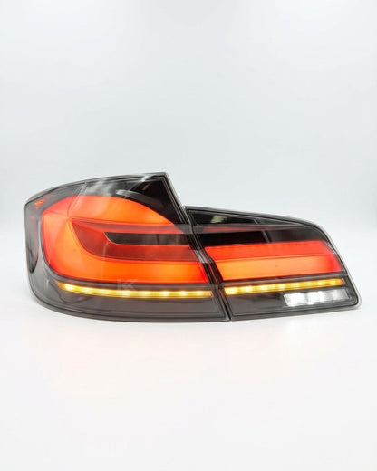 BMW 5-Series F10 F18 clear tail lights with G30 style from K2 Industries, showing the sleek design and bright illumination.