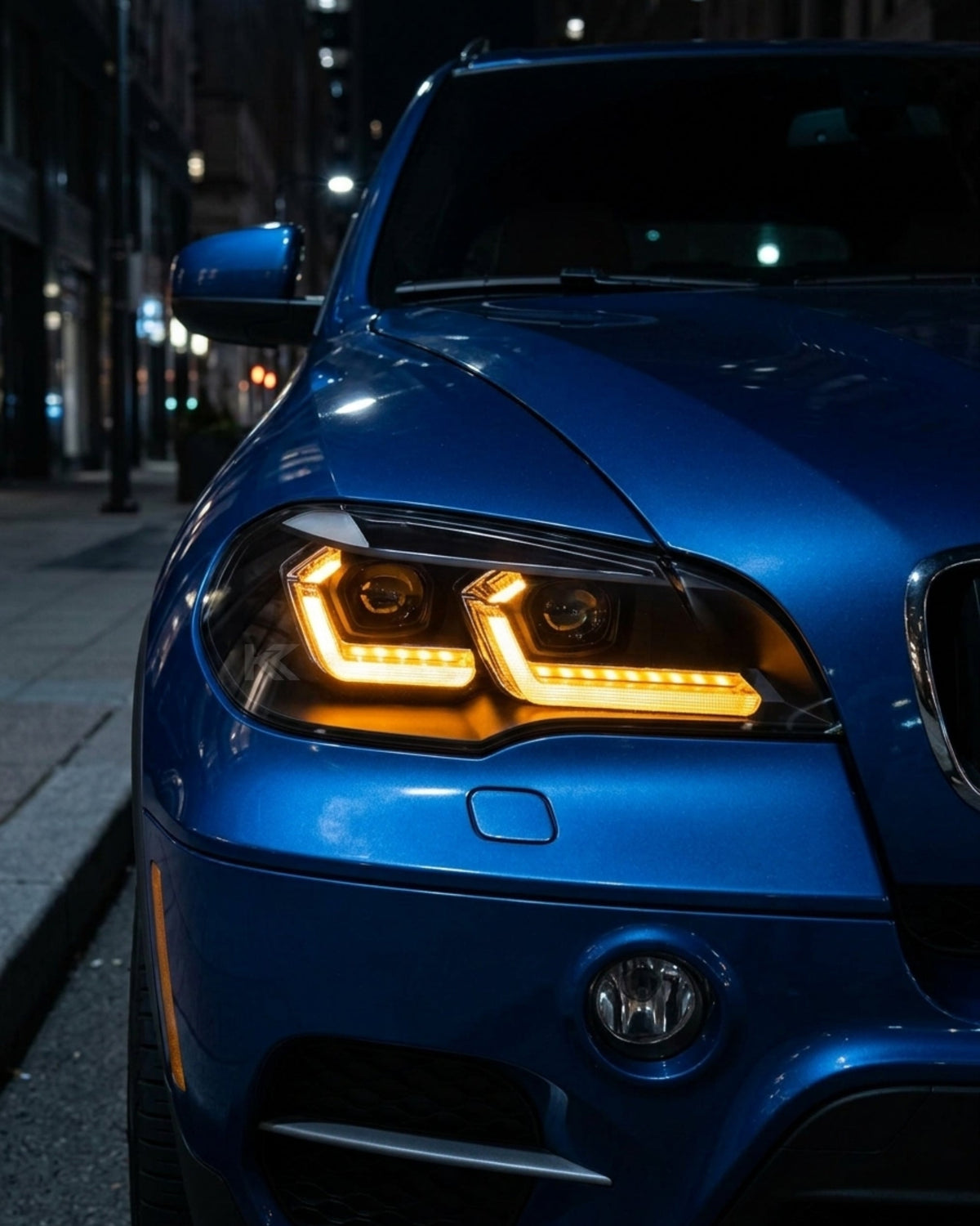 BMW X5 E70 headlights with K2 Industries "TRON" LED design installed, showing the front view with clear lens and LED accents.