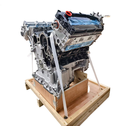 A large AUTOMOTIVE EA897 CATA AUDI VW 3.0L TDI engine block with attached components, photographed on a white background while sitting on a wooden crate secured with straps. 