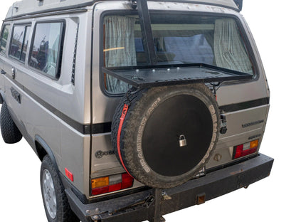 GoWesty tray-on spare bracket bundle with spare tire carrier for Bus and Vanagon vehicles, mounted on vehicle exterior.