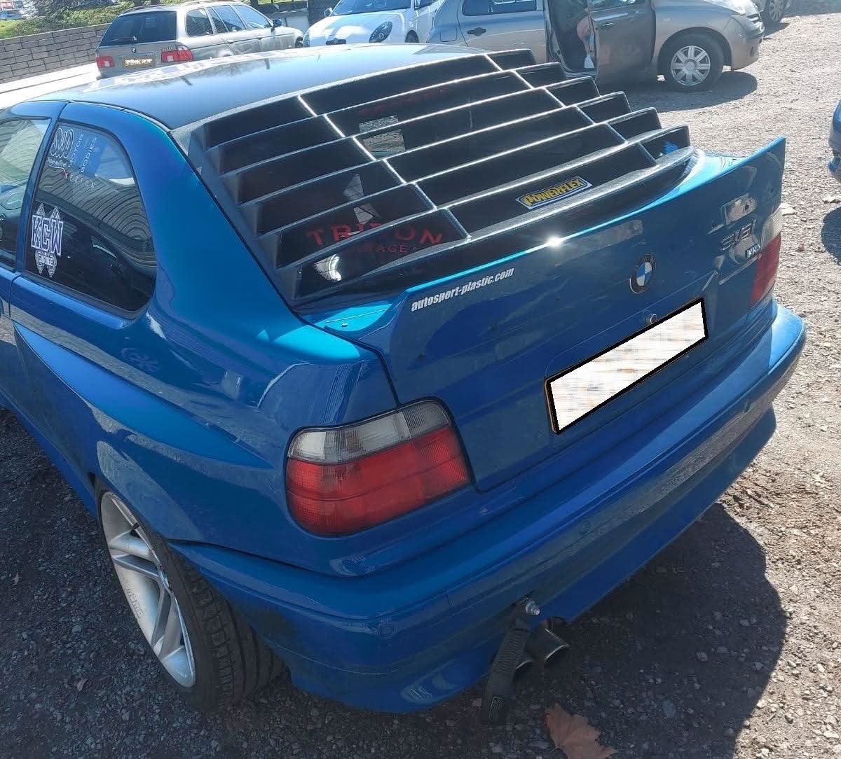 Black BMW E36 Compact Series 3 windshield louvers by K2 Industries, designed for 1992-1999 models, shown on the back windshield.