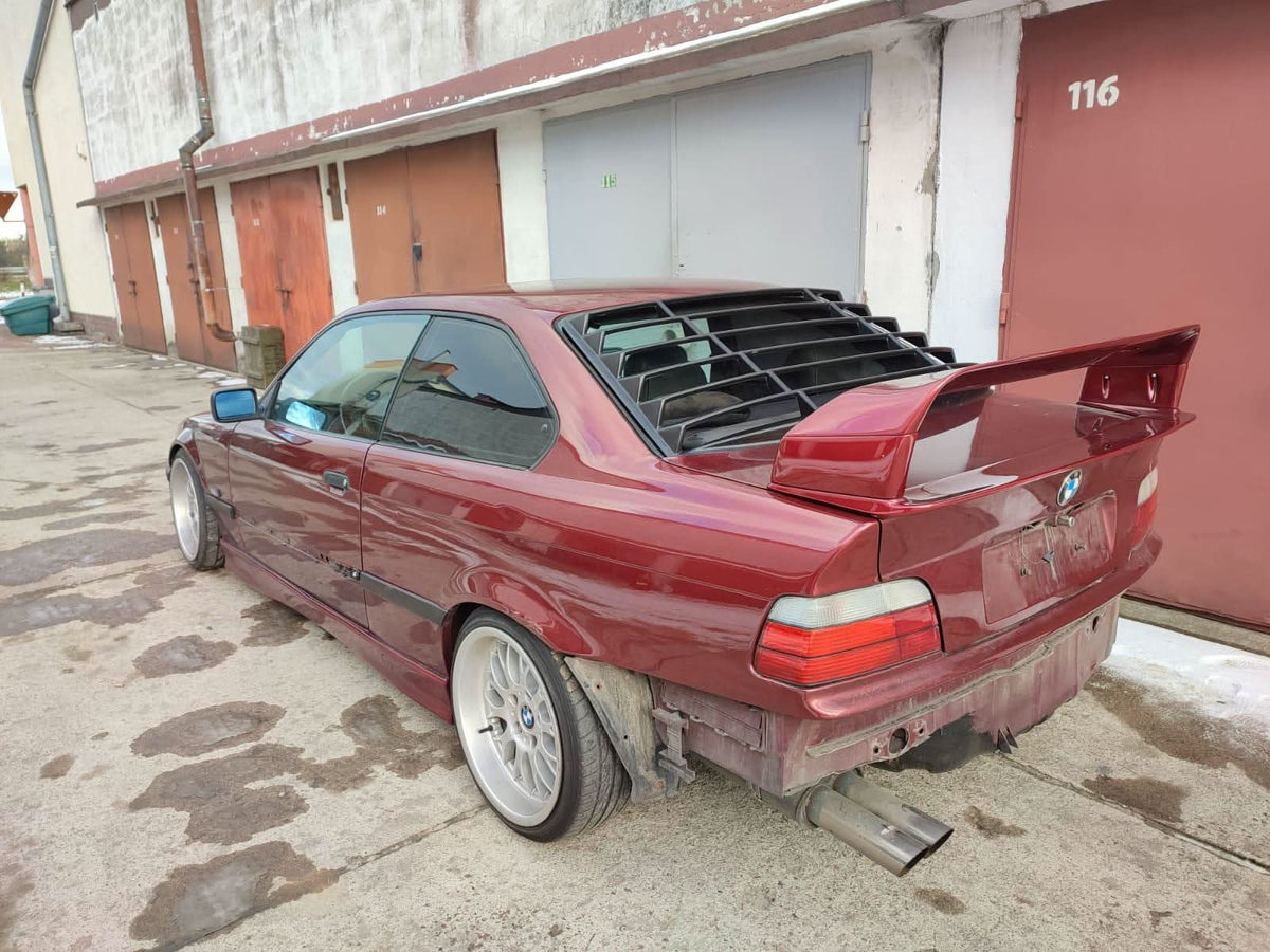 Black BMW E36 Coupe Series 3 windshield louvers by K2 Industries, located on the back window, from 1992 to 1999.