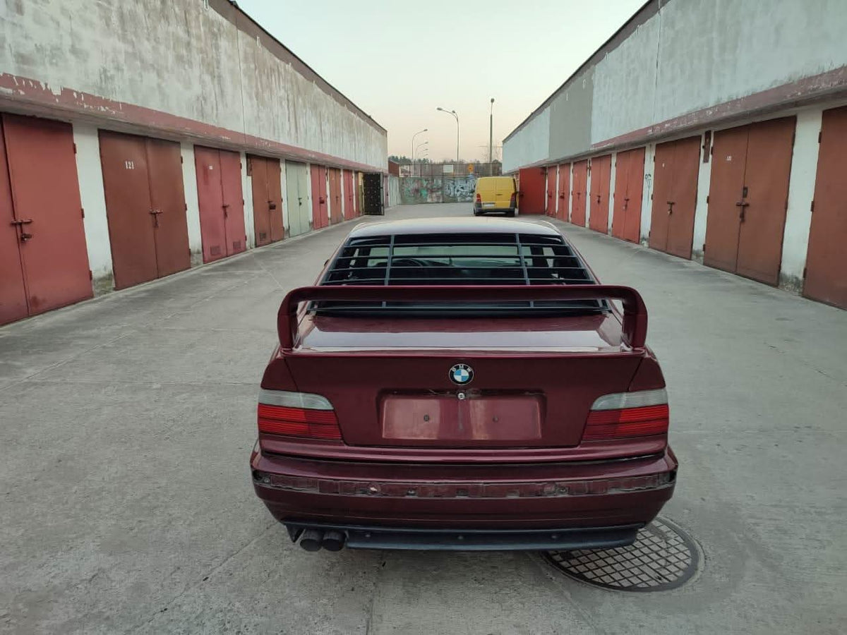 Black windshield louvers for BMW E36 Coupe Series 3 by K2 Industries, installed on the rear window of a 1992-1999 model.