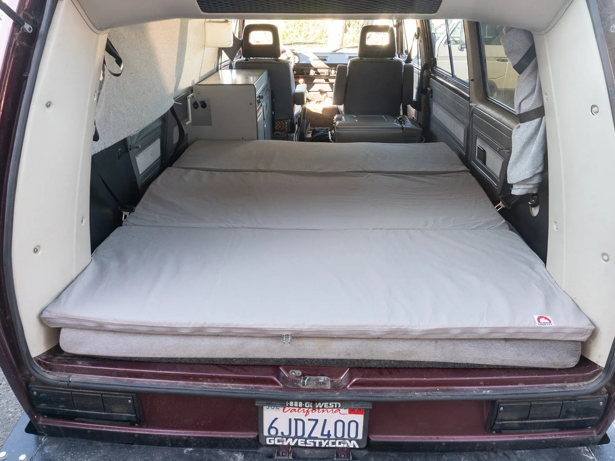 GoWesty slip-cover for large mattress topper, soft fabric protective cover showing a snug fit over the topper in a bedroom setting.